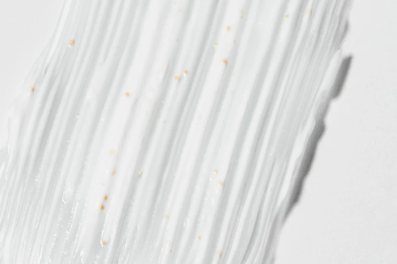 White cream spread in long strokes, flecked with small amber beads
